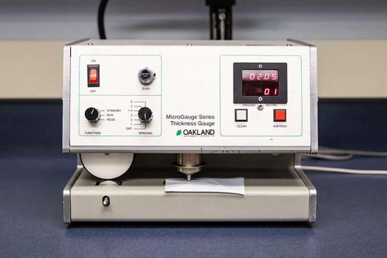 Micrometer and gram scale equipment used for precise measurements of material thickness and weight in packaging and manufacturing.